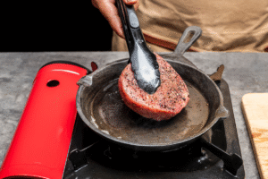 Adding steak to hot cast iron skillet